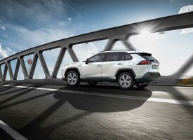 Der Suzuki Across fährt im Gegenlicht auf einer Brücke. Die Sonne scheint an den Brückenträgern vorbei.