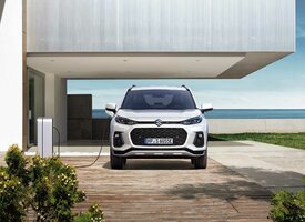 Der Suzuki Across steht auf dem Parkplatz eines Einfamilienhauses und wird an der Ladesäule geladen