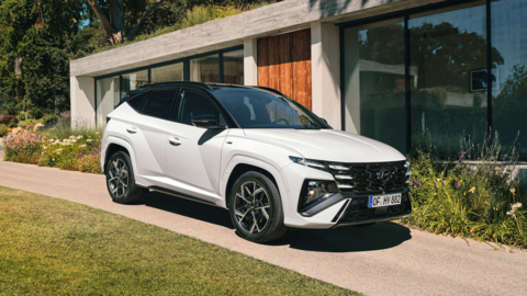 Foto eines weißen Hyundai TUCSON vor einem Haus mit Rasen